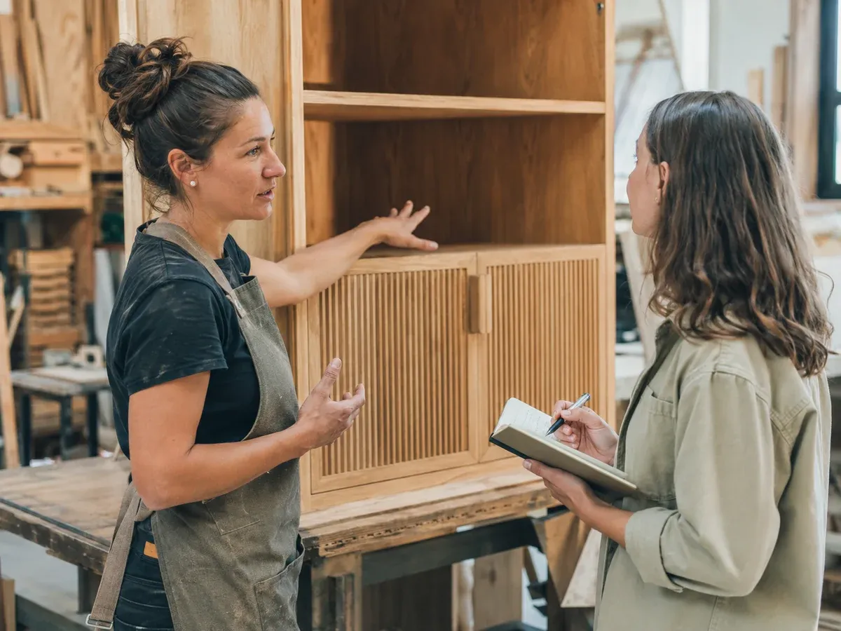 Carpenter sharing the details of a completed cabinet with a writer